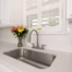 Updated kitchen sink with white quartz countertops, white subway tile backsplash, and plantation shutters.